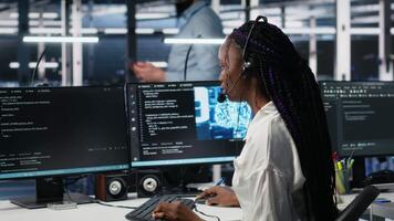 administration i data Centrum bär headsetet bistå användare med artificiell intelligens felsökning. afrikansk amerikan kvinna i server rum nav hantera Stöd biljetter använder sig av automatiserad system, kamera en video