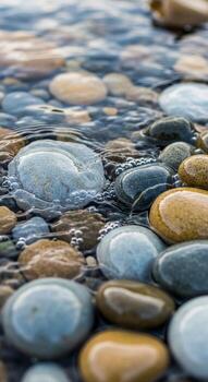 Smooth colorful river stones submerged in clear rippling water creating a serene and natural abstract pattern of light and texture photo