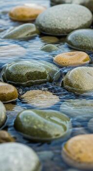 Smooth rounded river stones submerged in clear rippling water creating a serene and calming natural abstract pattern photo