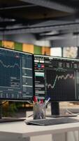 Vertical Stock exchange metrics insights displayed on computer screens in hedge fund business office. PC monitors on desk with financial software interface visible in forex company workspace video