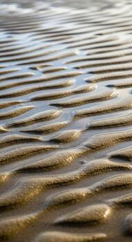 Ripples of sand and water create a textured abstract pattern on a beach at low tide photo