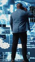 verticale nero imprenditore utilizzando mobile Telefono chiamata per interagire con le persone, azioni intuizione su cibernetico piattaforme e ai interfacce. macchina apprendimento e predittivo analitica per crescita. telecamera un. video