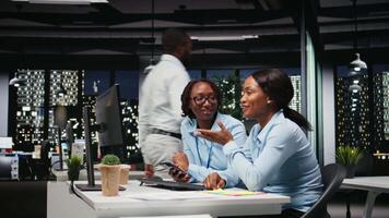 Black team of associates doing overtime with digital tech and insights to improve growth strategy, reviewing financial insights to foster innovation and development in office environment. Camera A. video