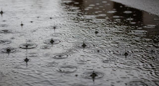 Dynamic Raindrops Creating Concentric Ripples on a Dark, Reflective Wet Surface, Capturing a Serene Moment. photo