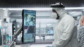 forskare i hazmat kostym kontroll dna molekyler av smittad patient i en biovetenskap labb, analyserar patologi och virologi data, testning immunologi teorier och utvecklande vacciner. kamera b. video