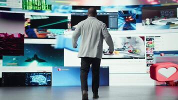 Overjoyed man with open arms facing large digital wall expressing happiness, benefiting from endless entertainment selection. Joyful viewer enjoying access to endless streaming options, camera A video