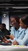 Vertical Black business people working together on report writing in dark office, collaborating on building a new development strategy after hours. Reviewing insights to enhance efficiency. Camera A. video