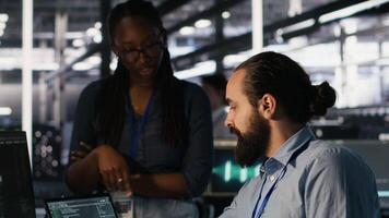 data Centrum systemet administratörer arbetssätt tillsammans, samarbetande på neuralt nätverk programvara utveckling. server nav arbetstagare och afrikansk amerikan kollega genomförande ai tech i arbetsplats, kamera en video