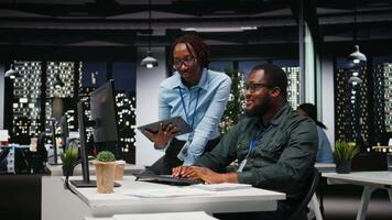 afrikansk amerikan arbetare grupp analyserar prestanda metrik på skrivbordet med hög teknik, inriktning företag strategi och mål till kör resultat inom en multinationell företag. kamera a. video