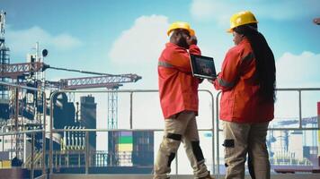 geolog arbetssätt för gas företag använder sig av bärbar dator programvara till bestämma optimal offshore borrning platser. pråm ingenjör ser på väl installation webbplatser data på anteckningsbok enhet, kamera en video