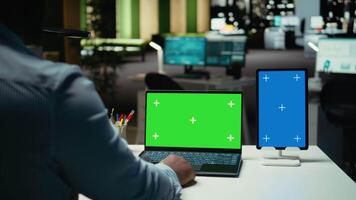 jong zwart consultant op zoek Bij blauw en groen scherm Aan apparaten, laat nacht werk sessie afwerking firma toediening taken na uur. gebruik makend van geïsoleerd Scherm Aan laptop en tablet. camera a. video
