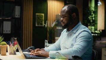 negro negocio consultor poniendo adhesivo Nota en ordenador portátil pantalla como un memorándum, molesto a recuerda un tarea desde su a hacer lista. trabajando tarde y dejando un recordatorio para siguiente Mañana. cámara b. video