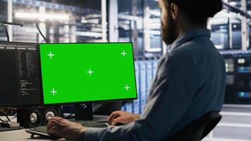 Data center technician doing software updates using green screen mockup computer. Server room IT specialist , optimizing infrastructure using chroma key isolated screen PC, camera A video