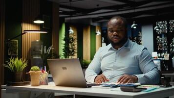 maschio azienda analista lettura dati rapporti e fatto controllo su computer portatile, pianificazione progetto e programmazione compiti dopo ore. prendere appunti e grafia per obiettivi risultato. telecamera un. video