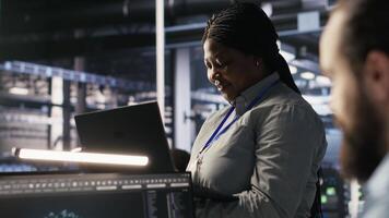 datos centrar gerente supervisando ingeniero desarrollando software a analizar neural redes a computadora puesto de trabajo. equipo líder y empleado observando sistema actuación en ai servidor habitación, cámara un video