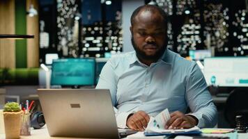 maschio azienda analista lettura dati rapporti e fatto controllo su computer portatile, pianificazione progetto e programmazione compiti dopo ore. prendere appunti e grafia per obiettivi risultato. telecamera b. video