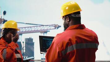 offshore plattform besättning använder sig av artificiell intelligens program på bärbar dator till optimera borrning operationer. afrikansk amerikan medarbetare analyserar geologi data använder sig av ai tech på anteckningsbok, kamera b video