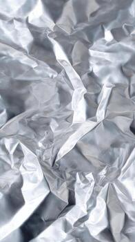 Crumpled Silver Foil With Textured Surface and Light Reflections in Clean Background photo