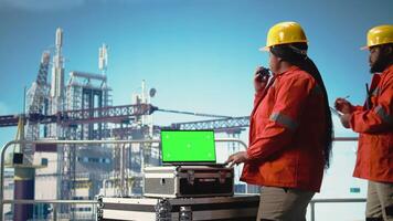 Grün Bildschirm Laptop benutzt durch Bohren rig Arbeiter mit Handheld Radio Gerät zu Monitor Systeme. Off-Shore Plattform Mitarbeiter mit Walkie Talkie, kalibrieren Ausrüstung mit Attrappe, Lehrmodell, Simulation Notizbuch, Kamera ein video