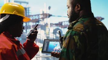 naval unidade em perfuração equipamento barcaça usando tábua para visualizar sistemas, salvaguardando a infraestrutura. exército soldado em no mar plataforma área coberta impede pirataria usando dispositivo para faço segurança plano, Câmera b video