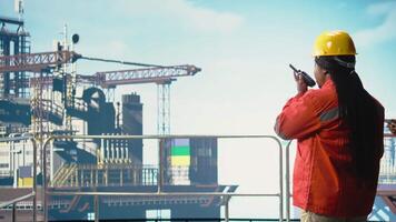 offshore plattform arbetstagare tala i walkie talkie, testning säkerhet systemet. radio operatör övervakar mekanisk och strukturell integritet av borrning rigg, hantera logistik flöde, kamera en video