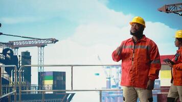 porträtt av Lycklig offshore plattform arbetstagare tala i walkie talkie, konfigurera borrtorn förvaltning system. leende borrning rigg arbetstagare håller på med havsbotten analys, talande i handhållen radio, kamera en video