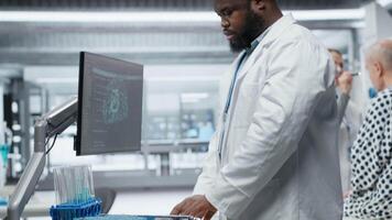 negro médico utilizando artificial inteligencia a observar efecto durante nuevo fármaco prueba, coleccionar farmacología datos con neural redes sistema. biomedicina descubrimiento y innovación. cámara b. video