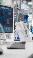 vertical cerca arriba de microscopio en laboratorio siguiente a computadora monitor mostrando adn datos y molecular análisis interfaz en laboratorio. bioinformática genómica software en ordenador personal y óptico dispositivo en estéril laboratorio video