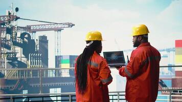 Offshore platform team using deep learning software on laptop to optimize drilling operations. Computer scientists on drilling rig ship analyzing geology data using AI technology, camera A video