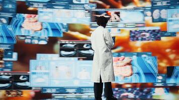 kvinna forskare ser på genomer på bärbar dator skärm, jämförande infektion modeller. afrikansk amerikan biomedicinsk ingenjör studerar patogener använder sig av anteckningsbok till design antiviral strategier, kamera en video