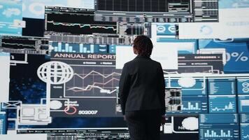 förvaltning verkställande jämförande företag metrik på digital videovägg innan framställning beslut. entreprenör analyserar nyckel prestanda indikatorer till optimera börja lönsamhet, kamera en video