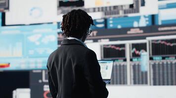 chef använder sig av bärbar dator programvara till jämföra företag metrik på digital videovägg innan framställning beslut. entreprenör analyserar nyckel prestanda indikatorer använder sig av anteckningsbok program, kamera b video