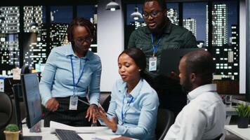 Black company employees reviewing data finances in an office meeting, consulting the analysis projection before developing a new growth strategy for the enterprise activity after hours. Camera A. video