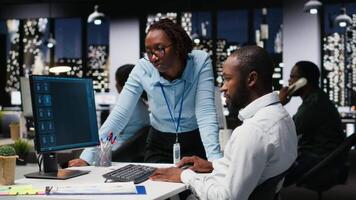 African american staff members use AI chatbot system at pc for problem solving tasks, futuristic high tech highlighting smart algorithms and deep learning. Communication and IT support. Camera B. video