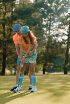 Pareja disfrutando golf práctica en soleado tarde a lozano verde curso con arboles en el fondo, demostrando trabajo en equipo y habilidad desarrollo en un relajado ajuste foto