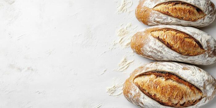 Three Golden Crust Sourdough Bread Loaves on White Floured Surface, Ideal for Bakery Promotions, Menu Design, or Food Blog Content photo