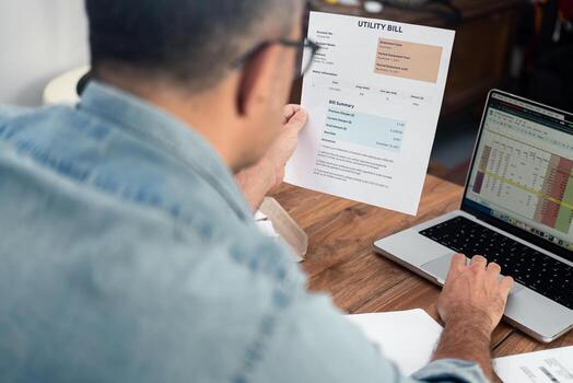 Mature man inputs utility bill data in digital spreadsheet working on computer, old male entrepreneur processes household expense count, regular payments organization photo