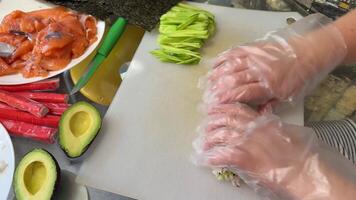 kock skivning lax och framställning sushi rullar med ost och gurka video