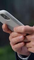 Close up male hands typing texting message browsing mobile phone in city unrecognizable business man businessman scrolling browsing smartphone social media application using gadget addict work online video