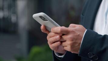 Close up male hands typing texting message browsing mobile phone in city unrecognizable business man businessman scrolling browsing smartphone social media application using gadget addict work online video