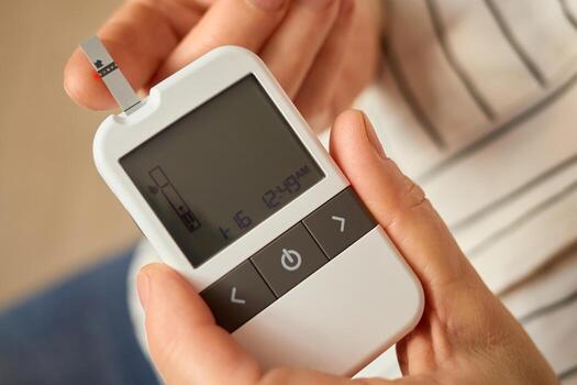 In a comfortable home environment, an individual is using a glucometer to monitor their blood sugar levels, showing a reading on the display screen. This activity is crucial for managing diabetes photo