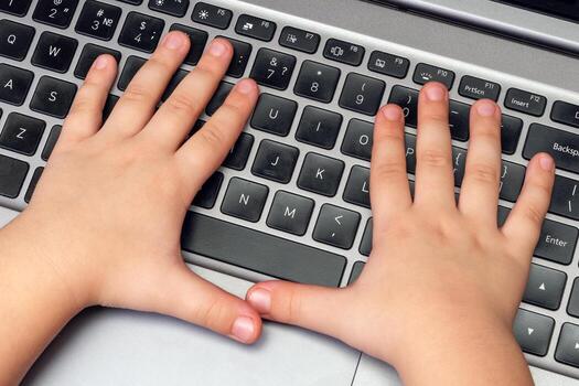 Child hands press buttons on laptop keyboard, child learning and playing on computer photo