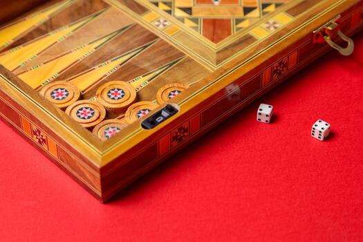 A fun game of backgammon. Checkers, dice, and a handmade board on a red background. photo