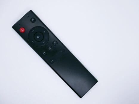 A black remote control with various buttons on a white background photo