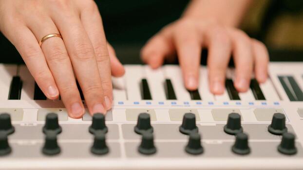 A Man Playing Synthesizer Keyboard MIDI Controller. Hands close up. Electronic Music Production concept. photo