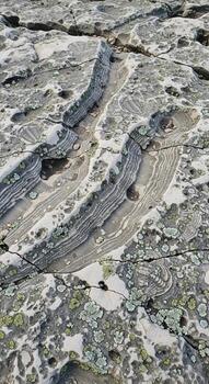 Close up view of weathered rock formations displaying intricate patterns of mineral veins and layered geological strata photo