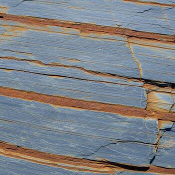 Close up view of weathered slate rock layers with striking rusty orange veins creating a natural abstract pattern photo