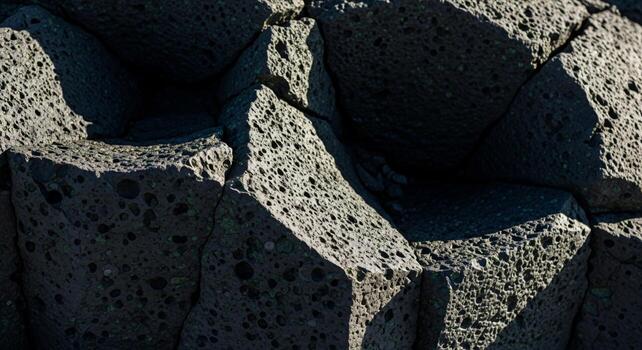 Close up view of dark textured basalt rock formations with sharp angles and deep shadows highlighting their natural geometric shapes photo