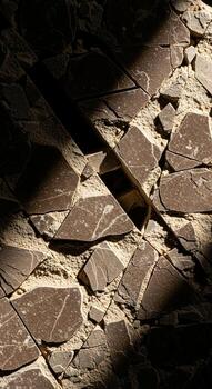 Textured stone wall with dramatic sunlight and shadow play creating geometric patterns and rustic charm photo