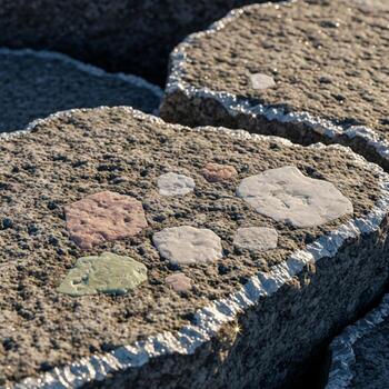 Close up view of weathered concrete blocks embedded with various colorful pebbles and stones showcasing natural textures and patterns photo